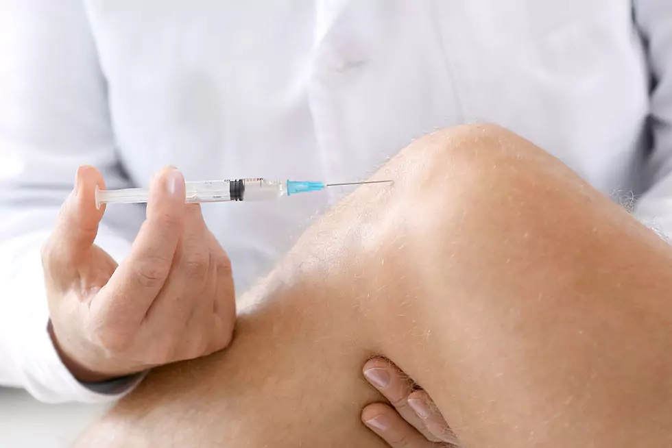 Arzt gibt Patient eine Spritze ins verletzte Kniegelenk