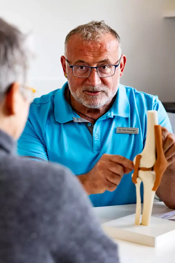 Arzt erklärt einer Patientin die Behanldungsschritte anhand eine Fußmodells
