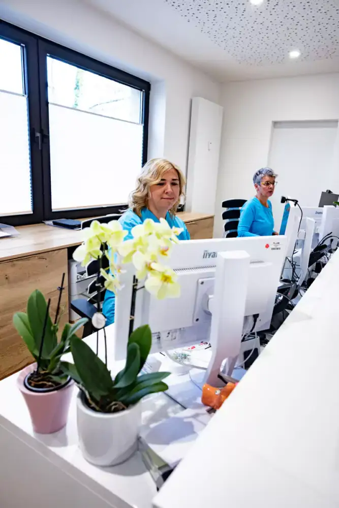 Mitarbeiterinnen am Empfang bearbeiten Daten am PC