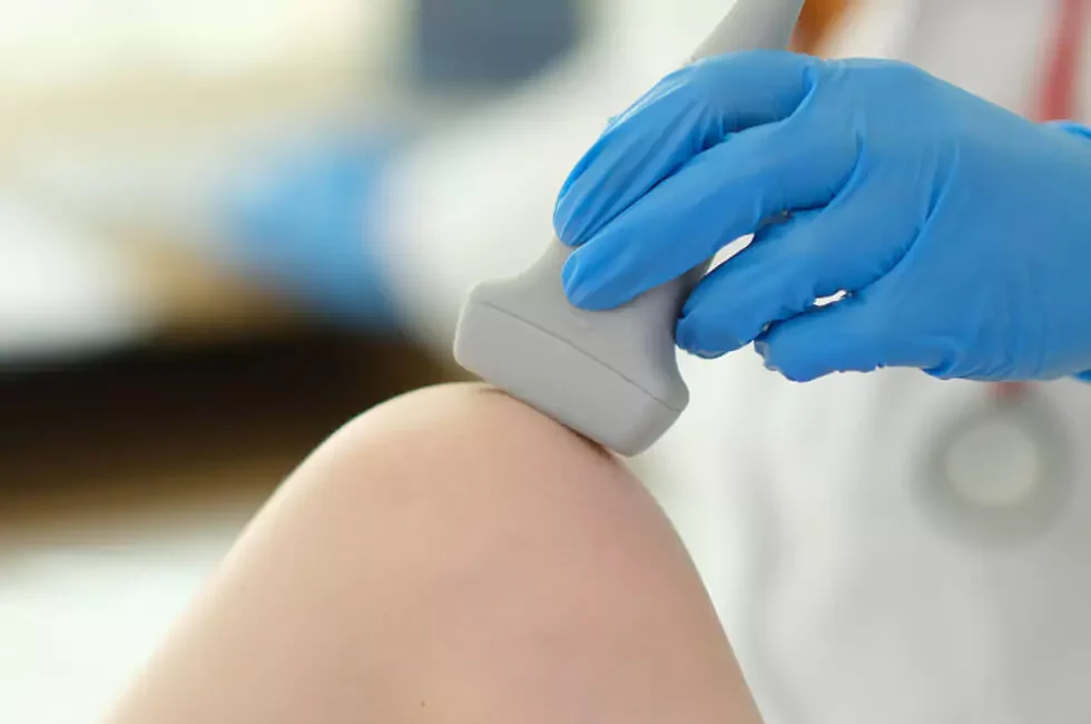 Orthopäde untersucht das Knie einer Patientin mit Ultraschall